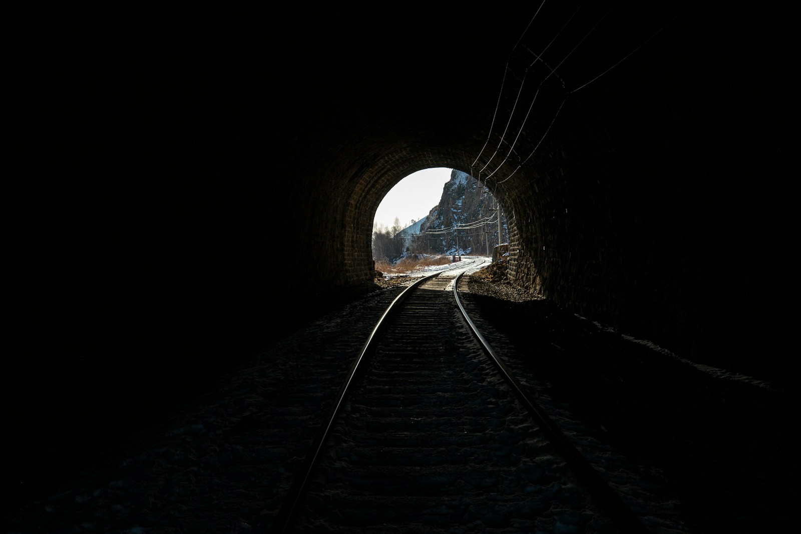 A dark tunnel with a train coming out of it